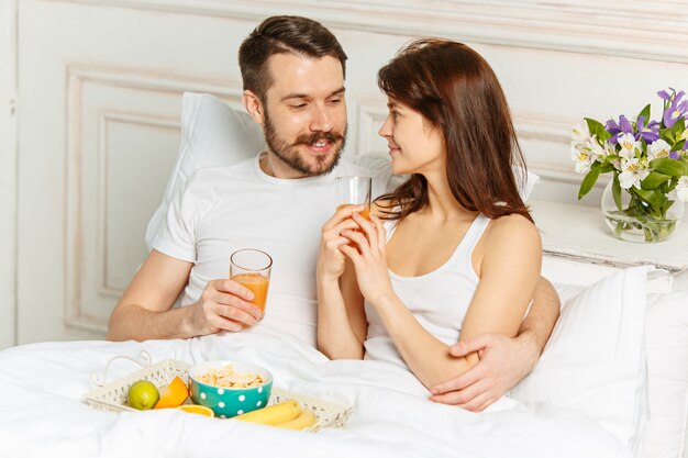 Young adult heterosexual couple lying on bed in bedroom