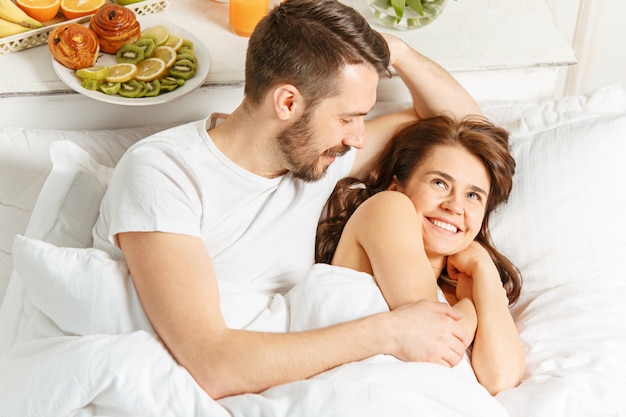 Young adult heterosexual couple lying on bed in bedroom