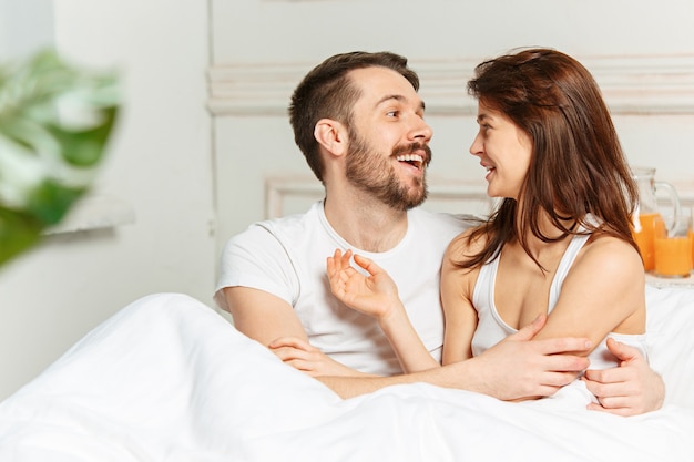 Young adult heterosexual couple lying on bed in bedroom