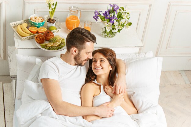 Young adult heterosexual couple lying on bed in bedroom