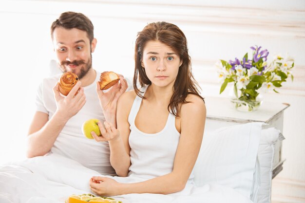 Young adult heterosexual couple lying on bed in bedroom