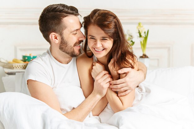 Young adult heterosexual couple lying on bed in bedroom