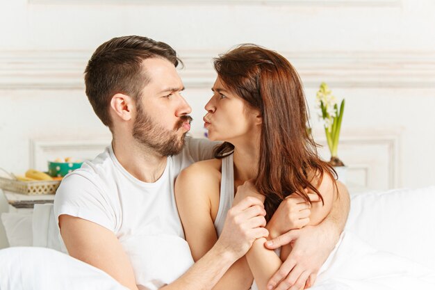 Young adult heterosexual couple lying on bed in bedroom