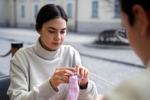 Giovani adulti che lavorano a maglia all'esterno