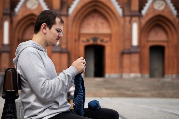 Free photo young adult knitting outside