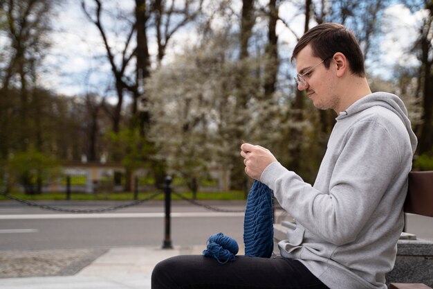 Free photo young adult knitting outside