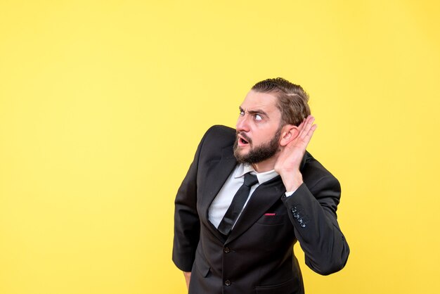 Young adult listening secret carefully standing over yellow