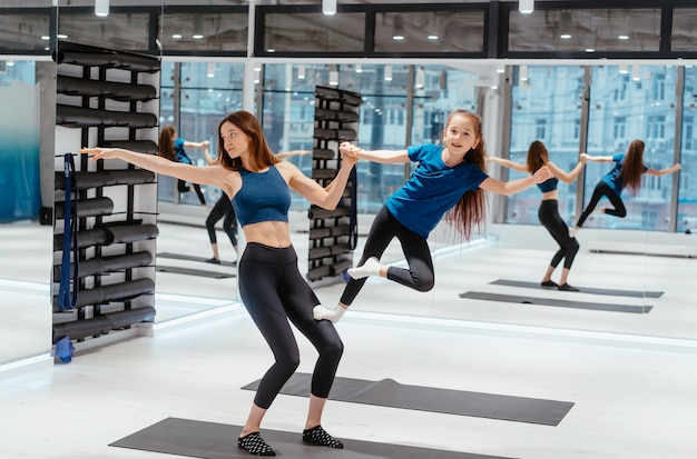 Young adult mother doing fitness with her little daughter