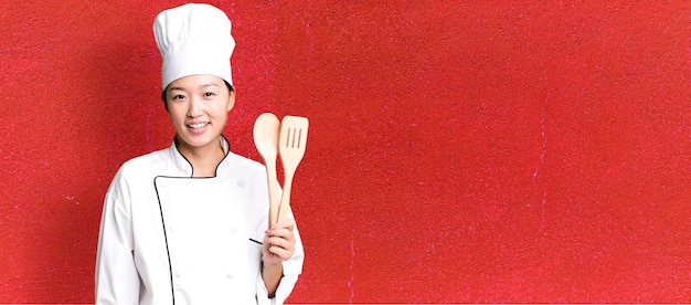 Foto gratuita cuoco unico adulto del ristorante della giovane donna abbastanza asiatica con uno strumento di legno