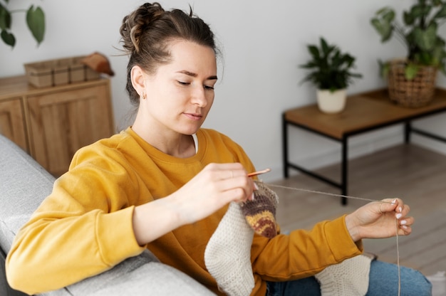 Foto gratuita giovane adulto che si rilassa mentre lavora a maglia