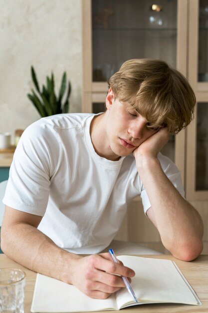 Молодой взрослый спит, делая домашнее задание