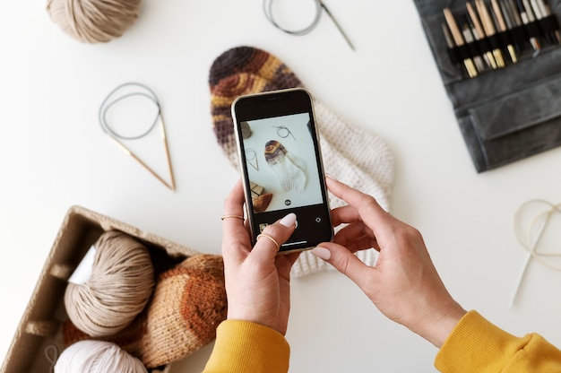 Young adult taking picture of their knitting product