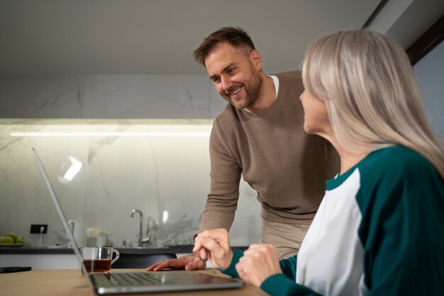 Young adult teaching elderly person about degital devicer