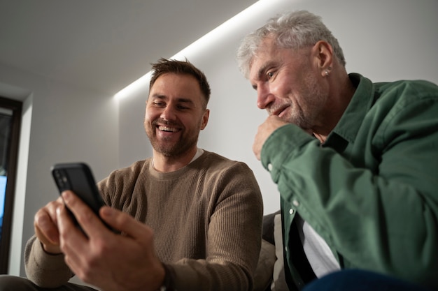 Бесплатное фото Молодой взрослый рассказывает пожилому человеку о дегитальном устройстве