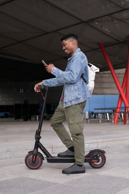 Молодой человек, использующий электрический скутер для перевозки