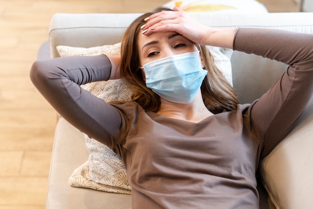 Young adult wearing a protection mask on couch