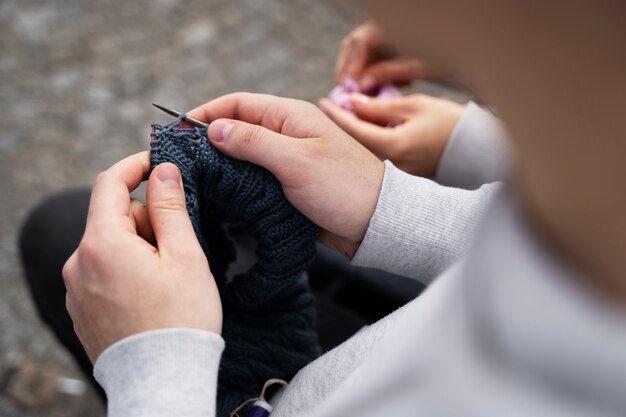 外で編み物をする若い大人