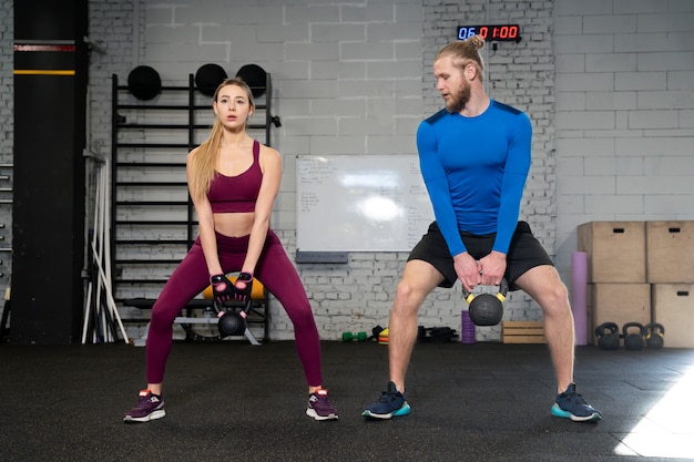 Young adults in sport gym using kettlebells