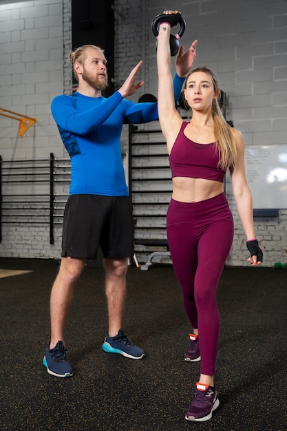 Young adults in sport gym using kettlebells