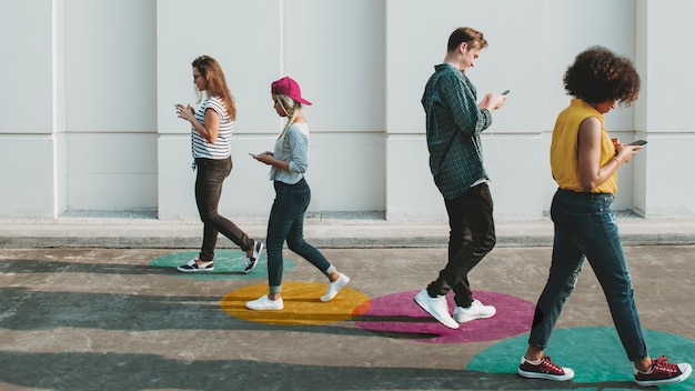 Foto gratuita giovani adulti che usano gli smartphone mentre camminano all'aperto