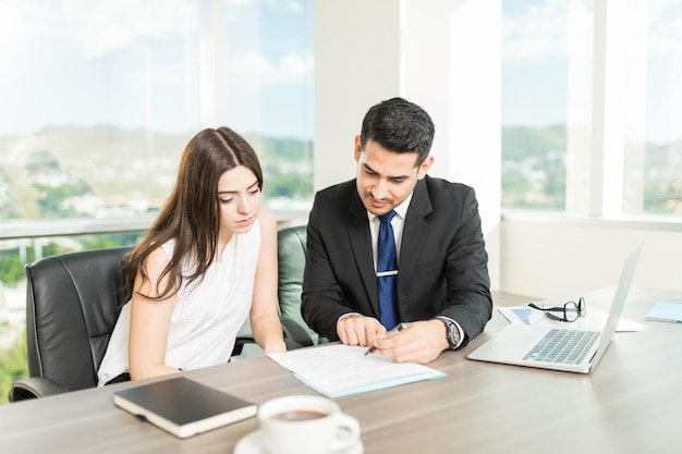 Free photo young adviser explaining legal document to client in his office