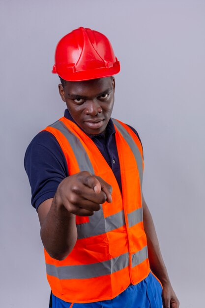 Young african american builder man wearing construction vest and safety helmet pointing displeased and frustrated angry and furious with you on isolated white