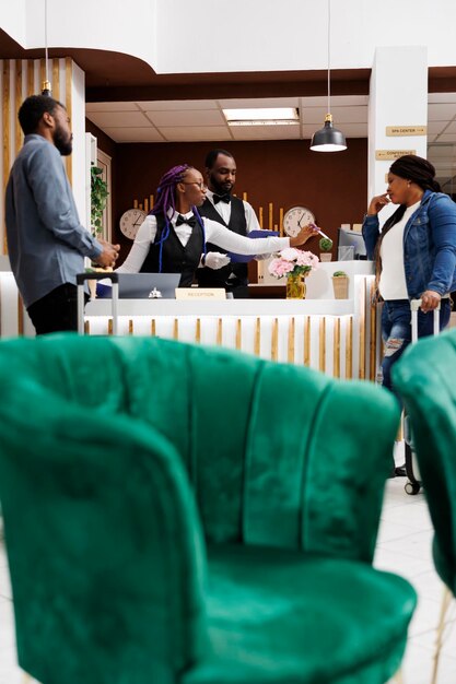 Young African American couple arriving at hotel, standing at reception with baggage talking with receptionist while checking in. Front desk agent getting information about guests during check-in