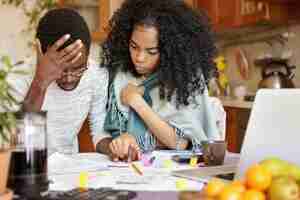 Free photo young african-american couple with many debts calculating gas and electricity bills