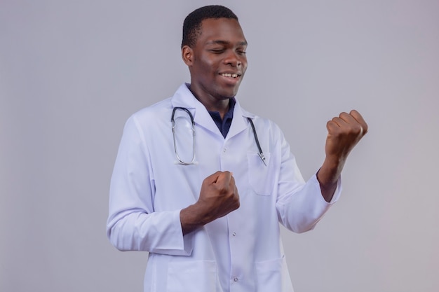 청진기와 흰색 코트를 입고 젊은 아프리카 계 미국인 의사가 종료하고 그의 성공을 기뻐하는 행복 떨림 주먹