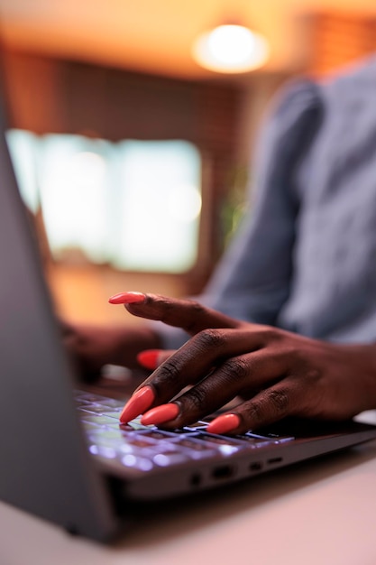 Giovane libero professionista afroamericano che digita sulla tastiera del laptop, vista ravvicinata sulle mani. donna d'affari che naviga in internet, scrive e-mail sul computer, si concentra su unghie curate