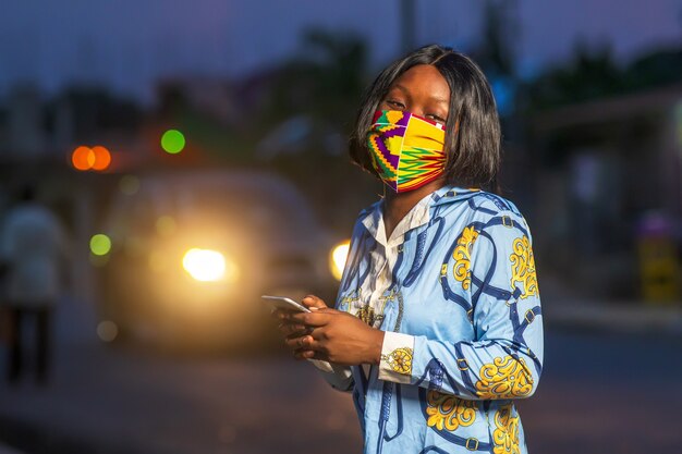 야외에서 화려한 보호 마스크를 쓴 젊은 아프리카계 미국인 여성