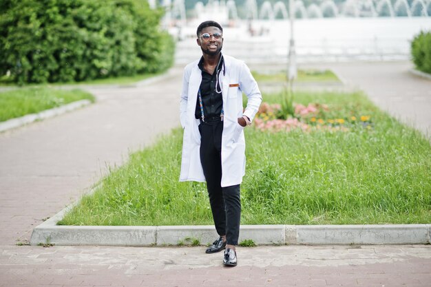 Young african american male doctor in white coat with a stethoscope posed outdoor