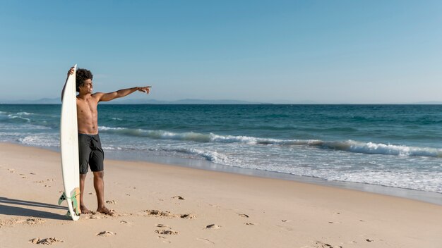 Бесплатное фото Молодой афроамериканец мужчина, указывая на океан