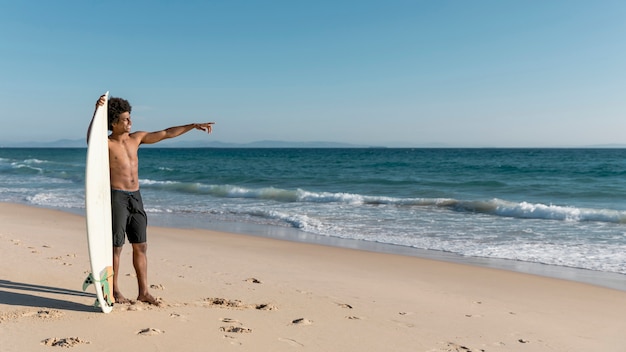 Young African American male pointing at ocean