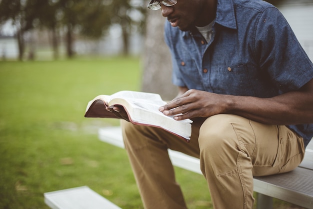 공원에서 성경을 읽고 앉아 젊은 아프리카 계 미국인 남성