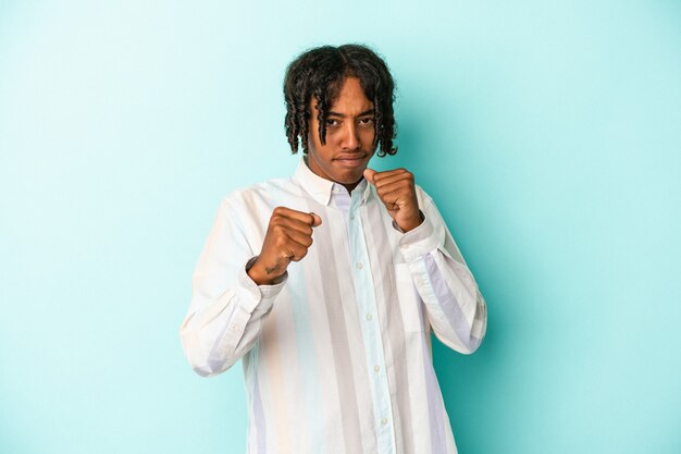 Young african american man isolated on blue background showing fist to camera, aggressive facial expression.