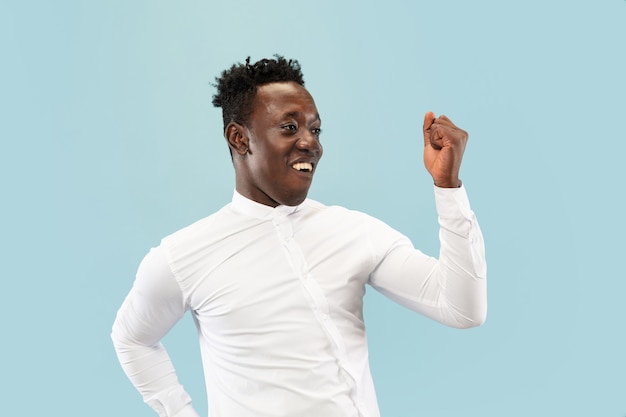 Young african-american man isolated on blue studio background, human emotions concept.