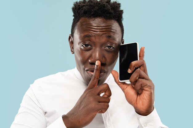 Young african-american man isolated on blue studio background, human emotions concept