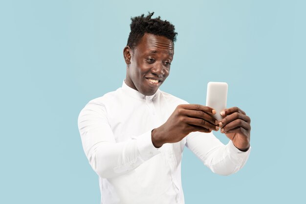 Young african-american man isolated on blue wall, human emotions concept.