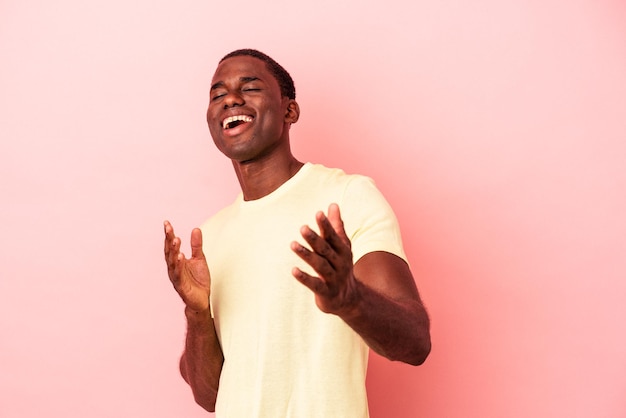 Young african american man isolated on pink background feels confident giving a hug to the camera. Premium Photo