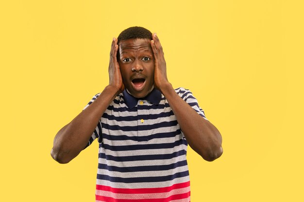 Young african-american man isolated on yellow studio background, human emotions concept.