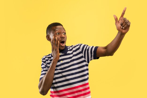 Young african-american man isolated on yellow studio