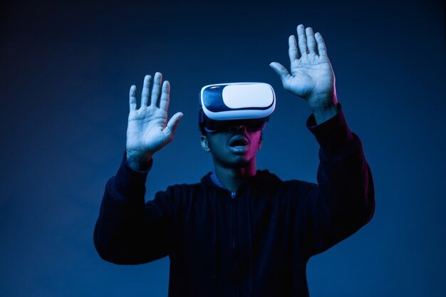 Young african-american man's playing in VR-glasses in neon light on blue