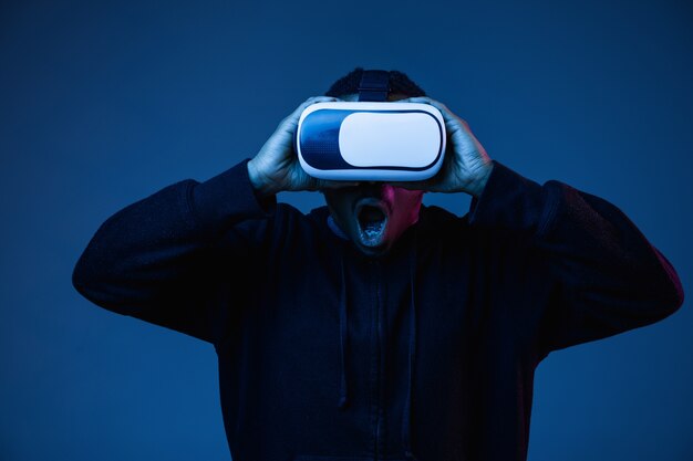젊은 아프리카 계 미국인 남자가 그라디언트에 네온 불빛에 VR 안경을 쓰고 있습니다.