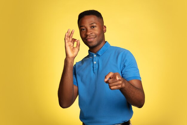 Young african-american man's portrait isolated on yellow, facial expression.