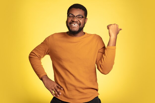 Young african-american man's portrait isolated on yellow, facial expression.