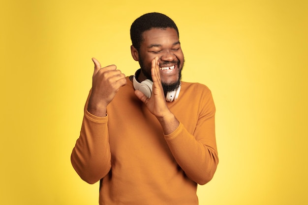 Young african-american man's portrait isolated on yellow, facial expression.