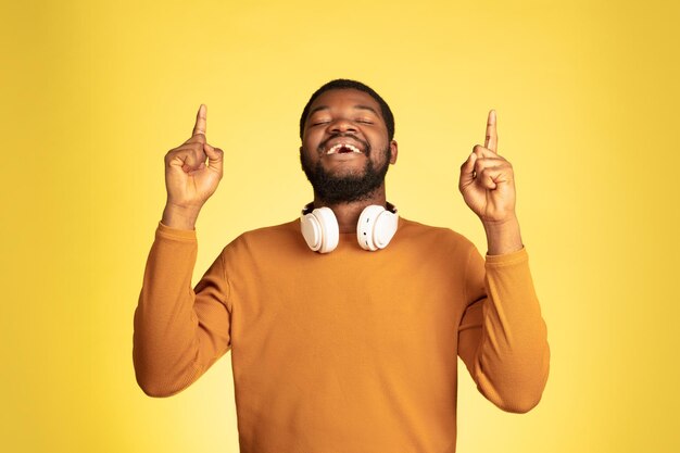 Young african-american man's portrait isolated on yellow, facial expression.