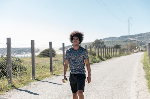 Giovane uomo afroamericano in abiti sportivi che cammina lungo la strada