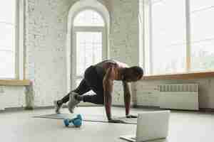 Free photo young african-american man training at home , doing exercises of fitness, aerobic.